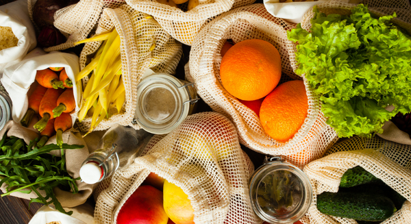 Gerne! Hier ist ein passender Alt-Text für das Bild:  Verschiedene frische Obst- und Gemüsesorten wie Orangen, Karotten, Gurken und Salat in wiederverwendbaren Stoffnetzen und Gläsern – nachhaltiger, unverpackter Einkauf.