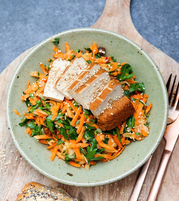 Schüssel mit frischem Karotten-Kräuter-Salat, belegt mit Sesam-Tofu.